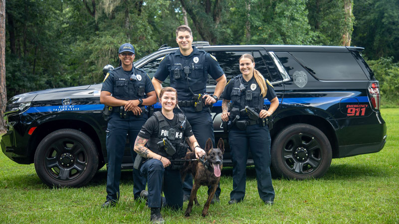 Officers posed with a patrol vehicle and K9